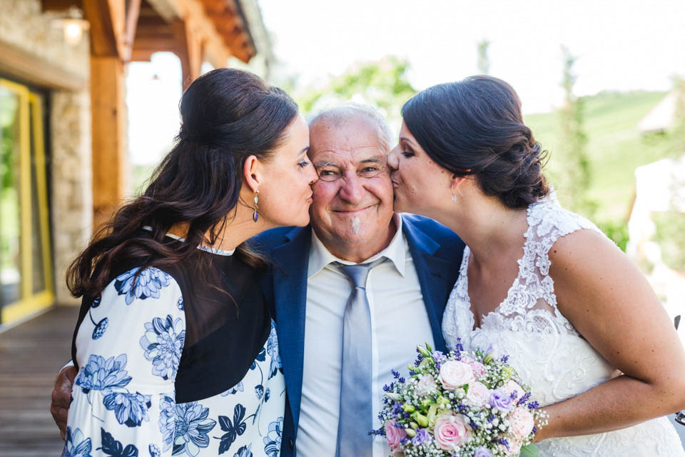 Die Braut und ihre Schwester geben dem Brautvater einen Kuss auf die Wange